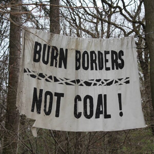 Bäume mit einem Plakat. Burn Borders, Not Coal von Hambach