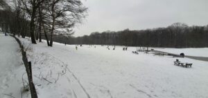 Berg mit Liegewiese und Spielenden Menschen im Schnee